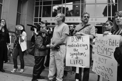 Woman on bullhorn and protesters with signs