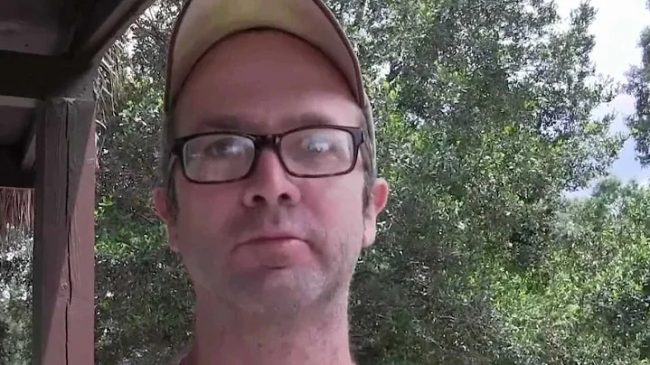 photo of middle age while male with short hair, baseball cap and black framed eyeglasses
